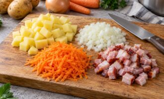 Нарезанные картофель, лук, морковь и копчёная грудинка